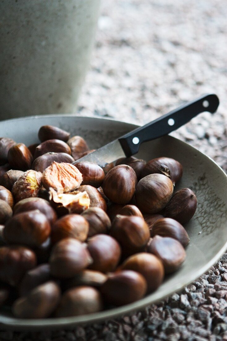 A bowl of chestnuts with a knife