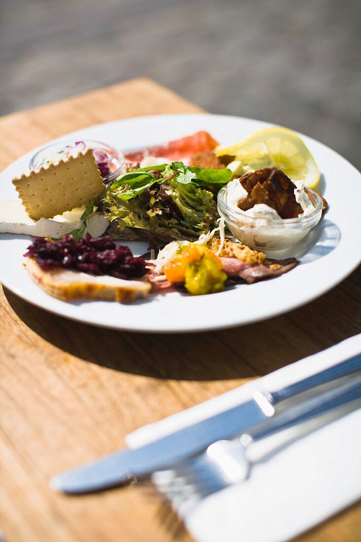 Vorspeisenteller mit Lachs und Gemüse auf Tisch im Freien