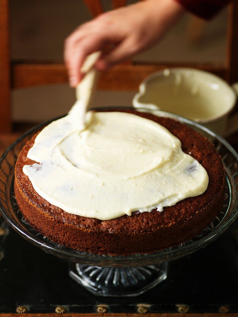 A chocolate cake being decorated with cream