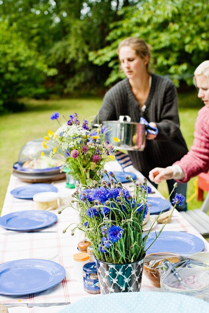 Frauen decken einen Tisch im Garten