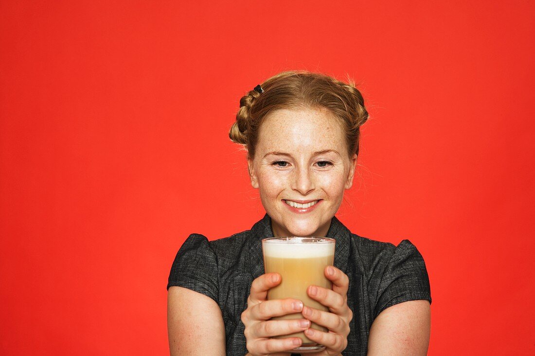 A smiling woman holding a glass of coffee