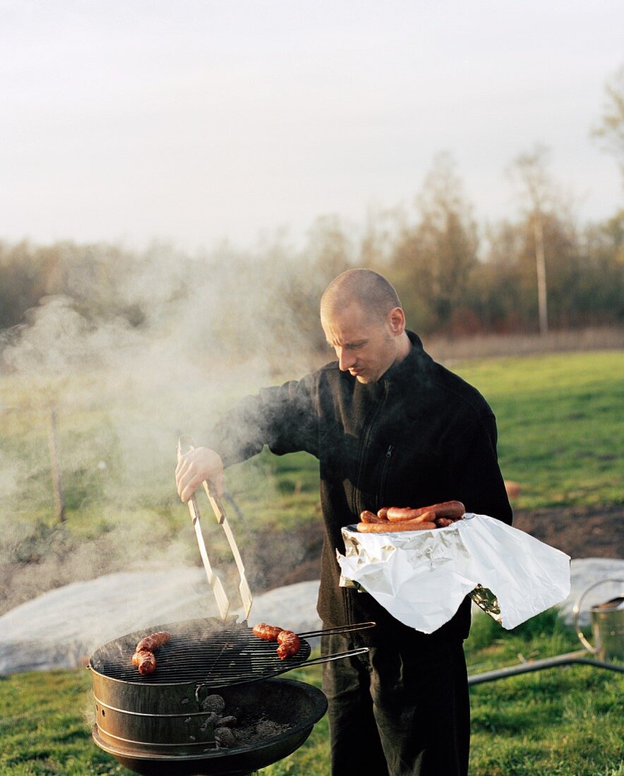 A man barbecuing sausages