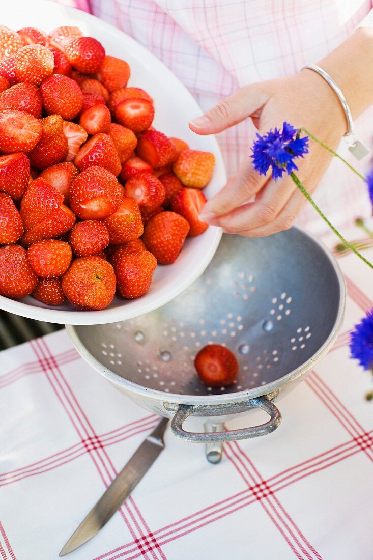 Fresh strawberries being poured into a colander