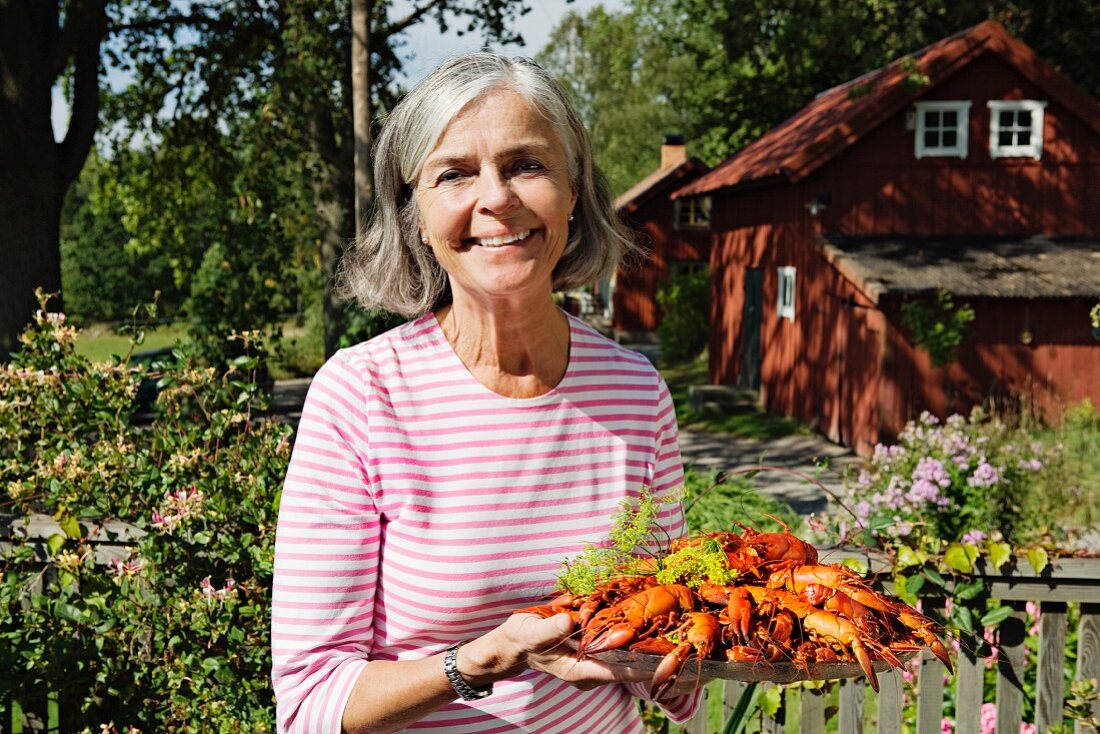 Frau serviert Teller mit Flusskrebsen (Schweden)