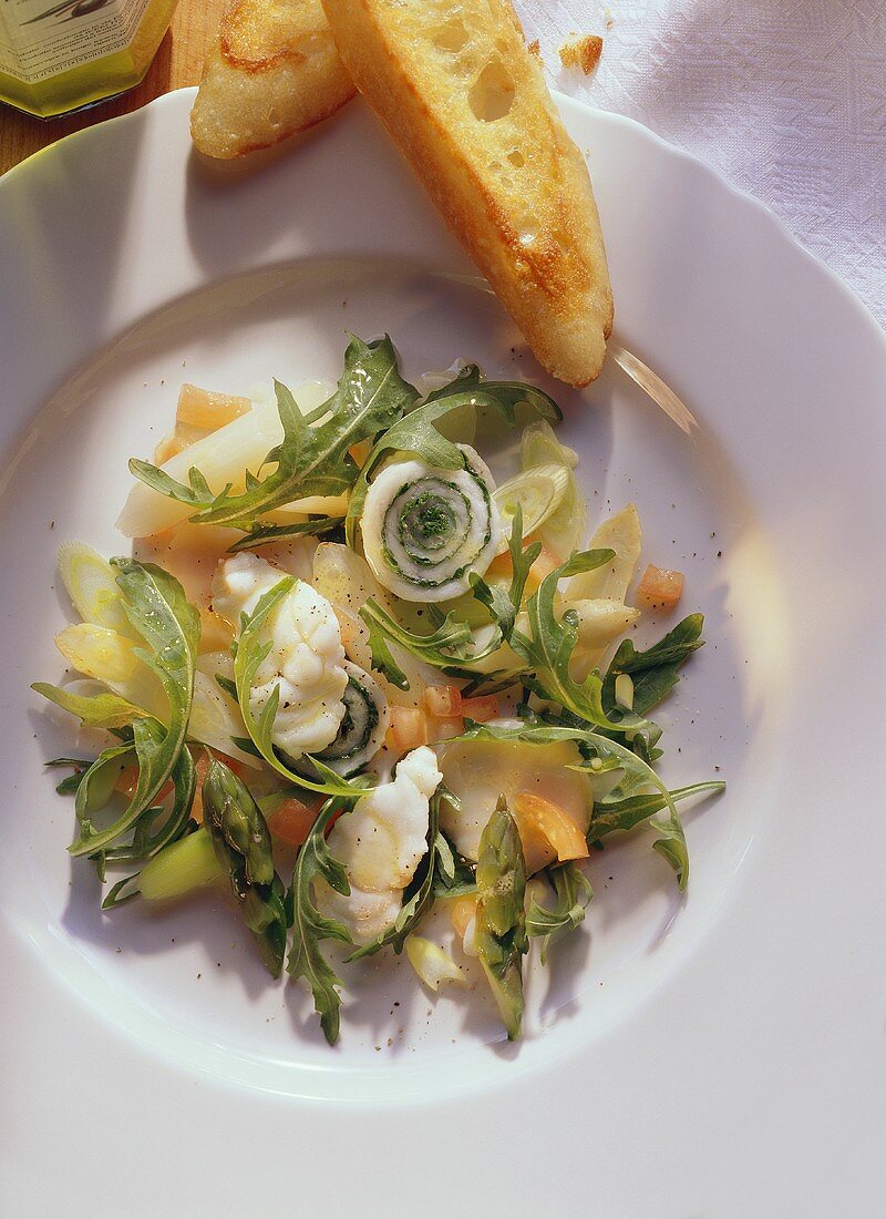 Feiner Fischsalat mit Spargel & Rucola auf weißem Teller
