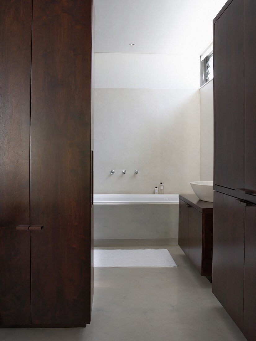 Badezimmer mit Schränken aus dunklem Holz in weißem Designerbad