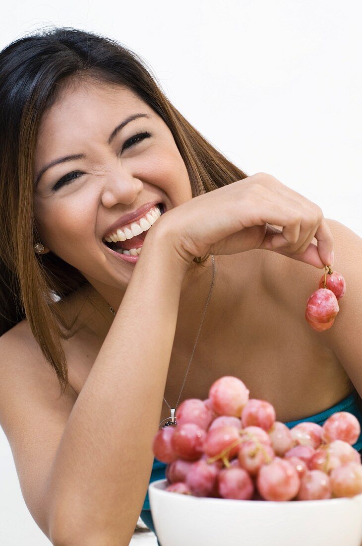 A young smiling woman eating grapes