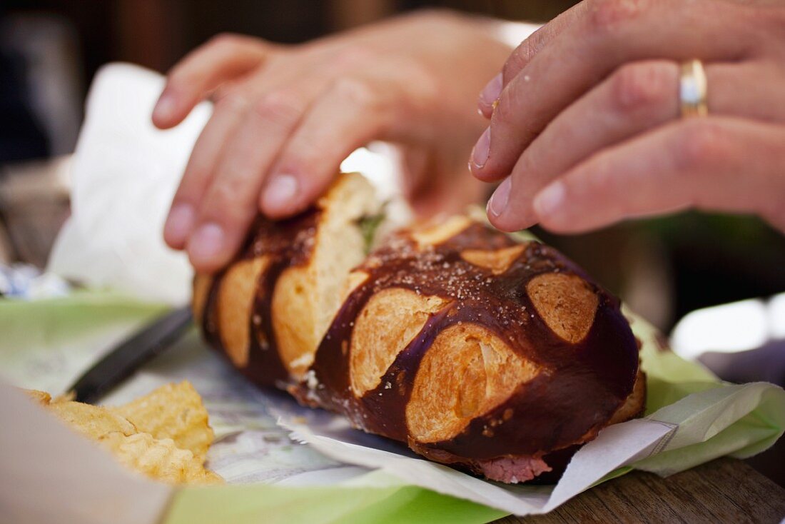 Hand Picking up a Corned Beef Sandwich on Pretzel Brioche (San Francisco California)