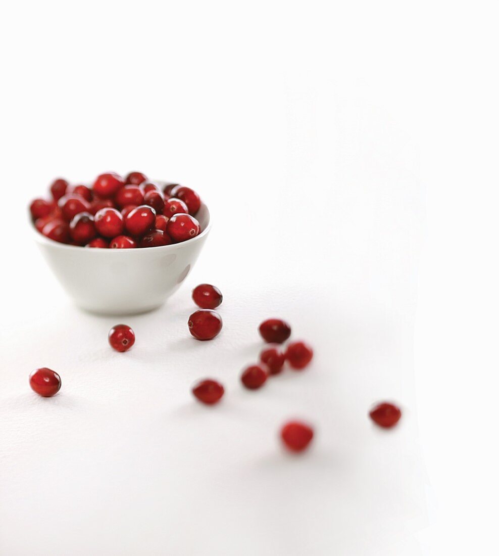 Fresh Cranberries in and Around a White Bowl; White Background