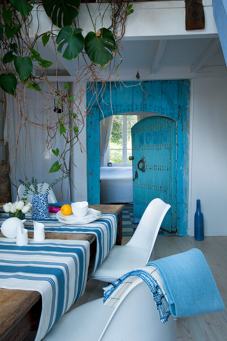 Dining room with blue and white striped tablecloth and antique blue wooden door