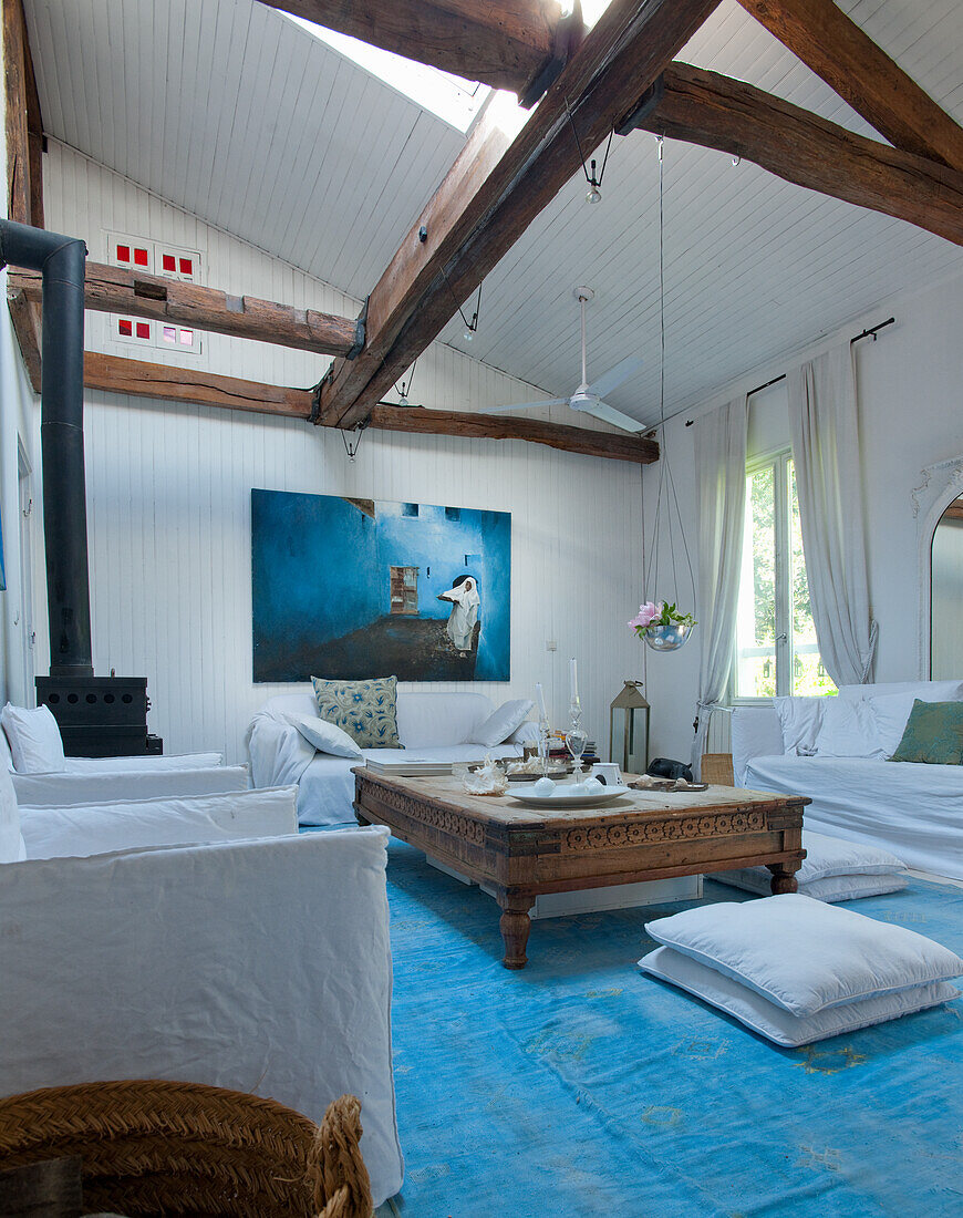 Living room with wooden beams, blue carpet and rustic coffee table