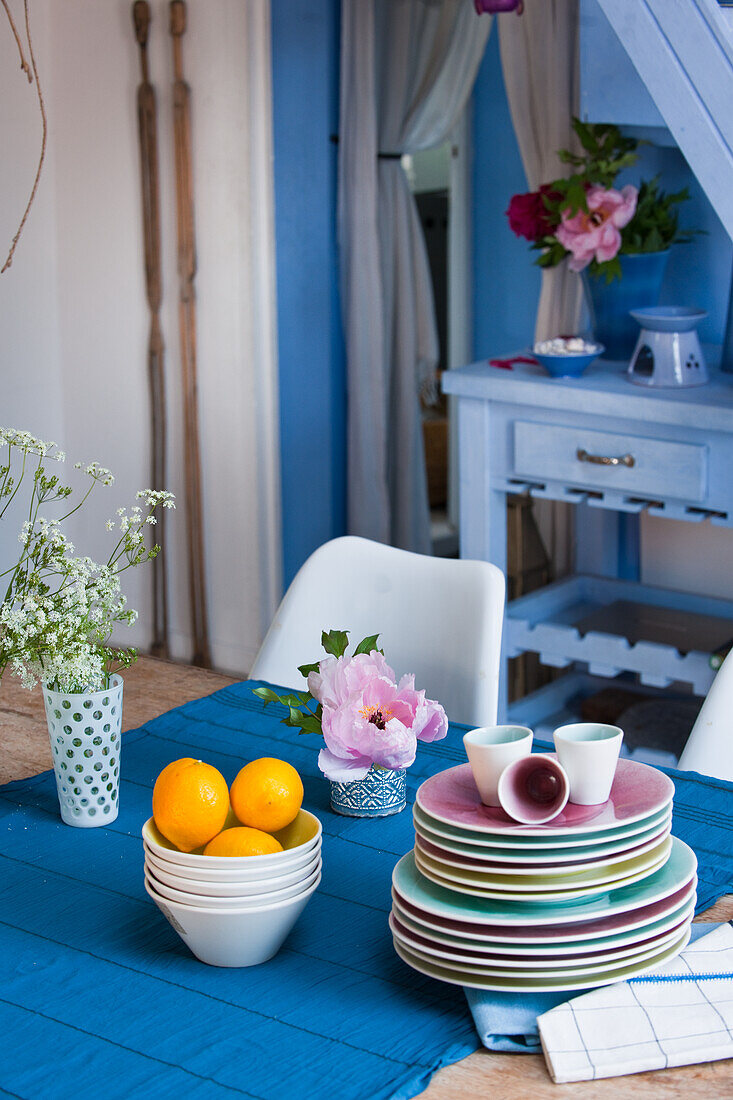 Crockery and flower arrangement on wooden table with blue table runner