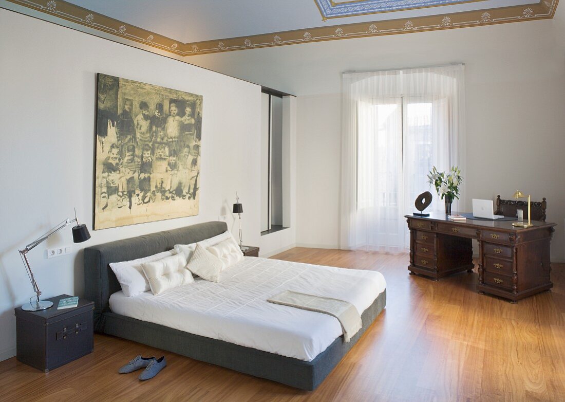 Modern double bed and antique desk in spacious bedroom