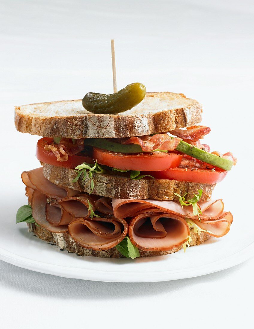 Club Sandwich with a Pickle and Toothpick; On a Plate; White Background