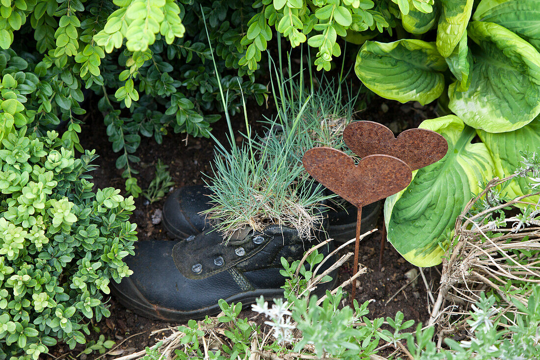 Alte Schuhe als Pflanztopf und rustikale Herzdeko im Garten