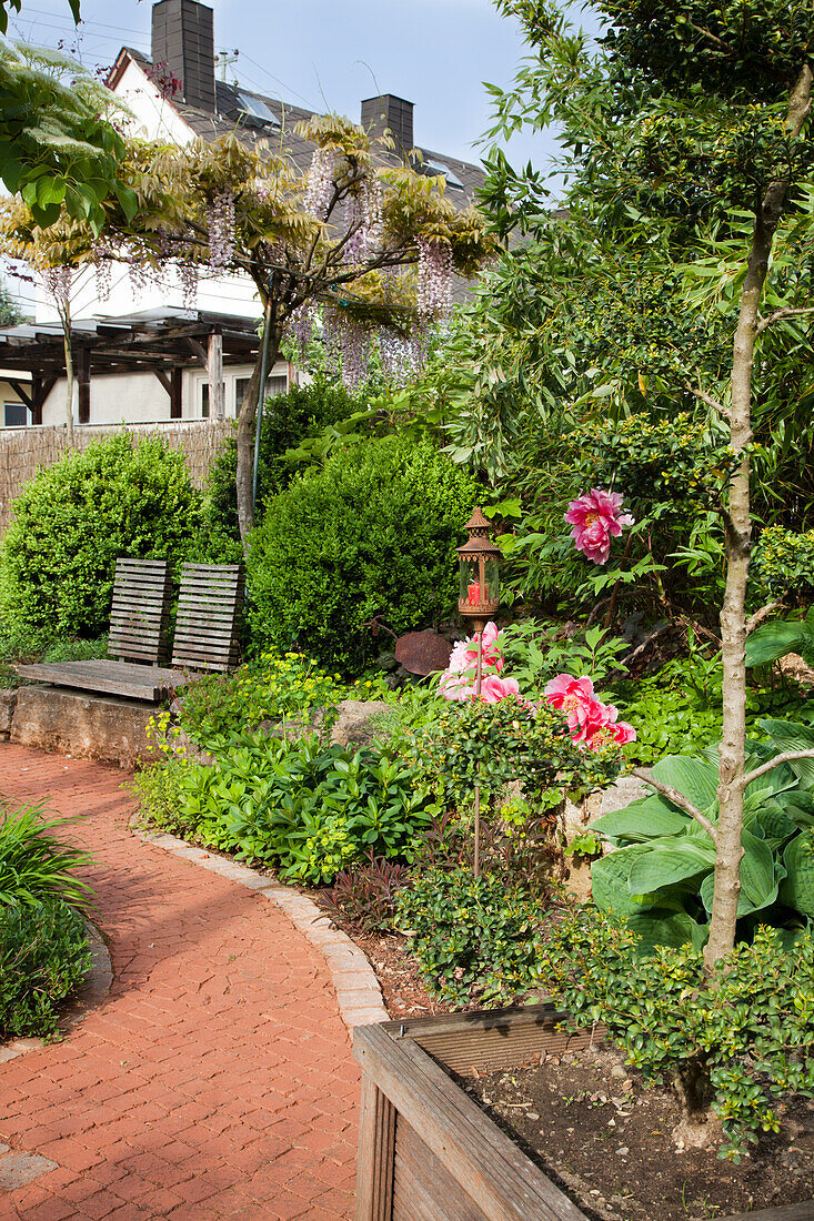 Gartenweg mit Pflanzen, Blüten und Sitzgelegenheit