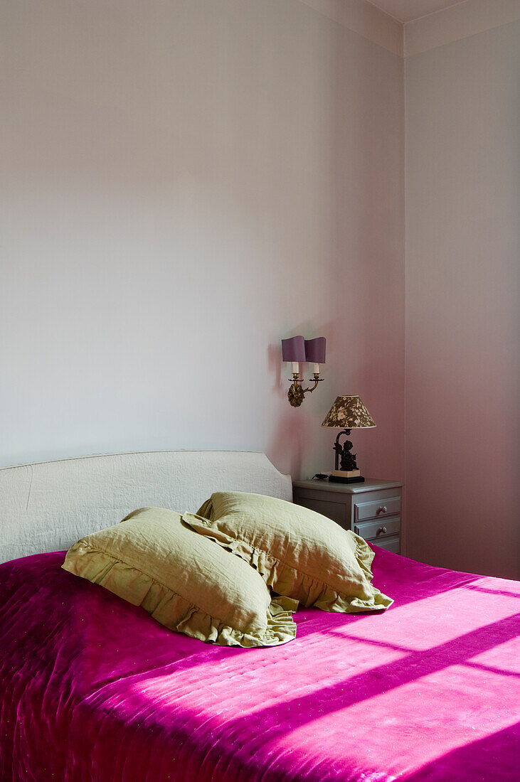 Bedroom with white bed, pink bedspread and light green cushions