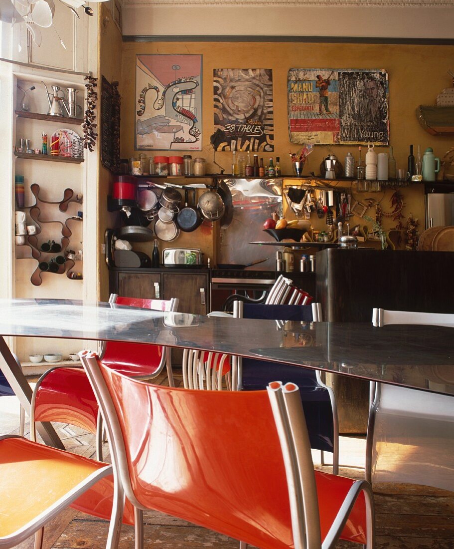 Stuhl aus orangem Kunststoff vor Metalltisch in nostalgischer Küche