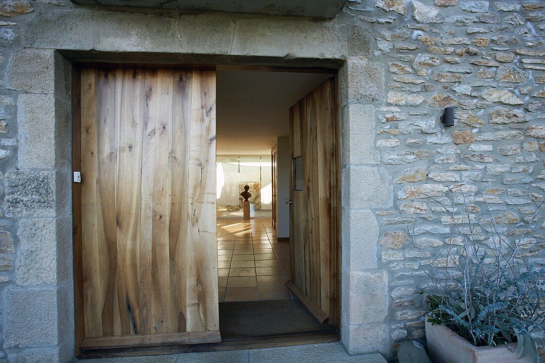Blick durch geöffnete Holztür in eine Halle mit Büste