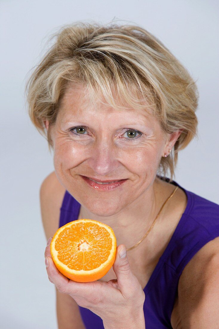 A woman holding half an orange