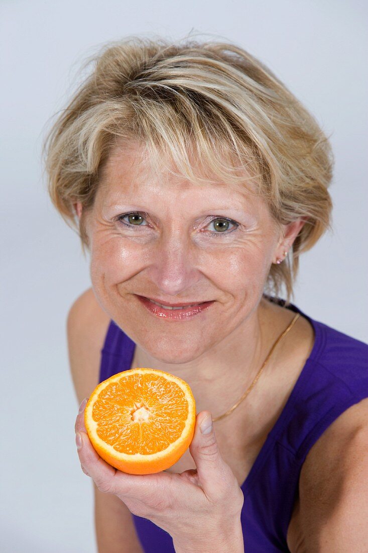 Frau hält eine halbe Orange