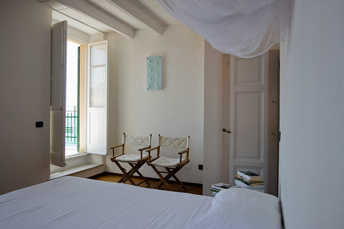 Brightly decorated bedroom with director's chairs, beamed ceiling and balcony access