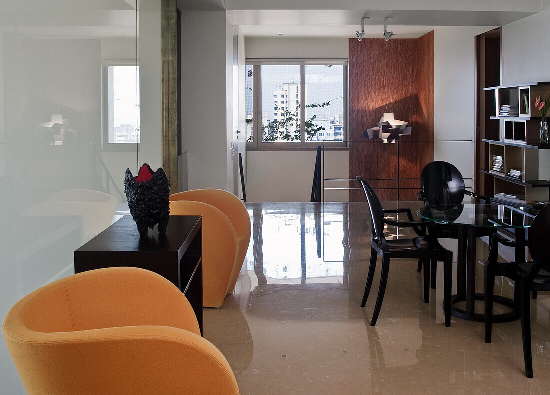 Modern dining room with dark furniture and orange-coloured armchairs