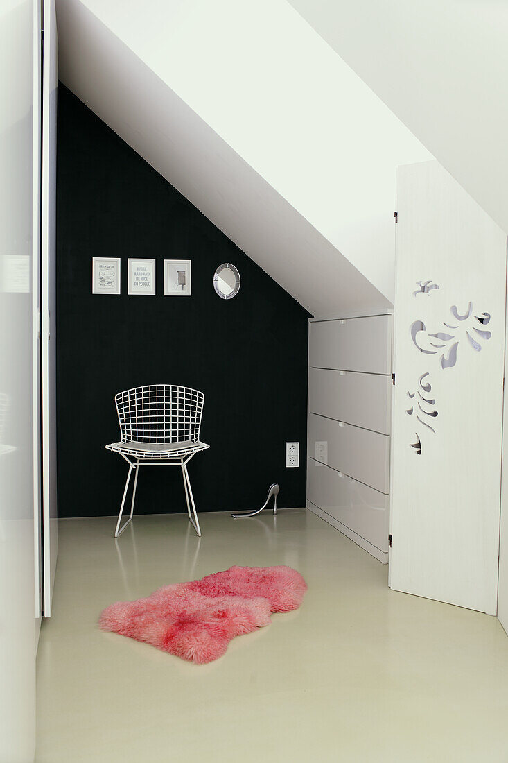 Room with sloping ceiling, black wall and pink fur rug