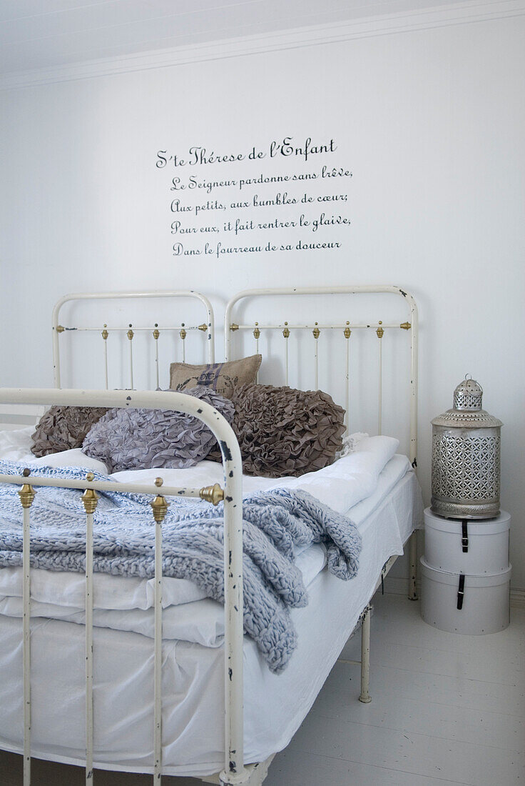 White metal bed with decorative pillows in bedroom