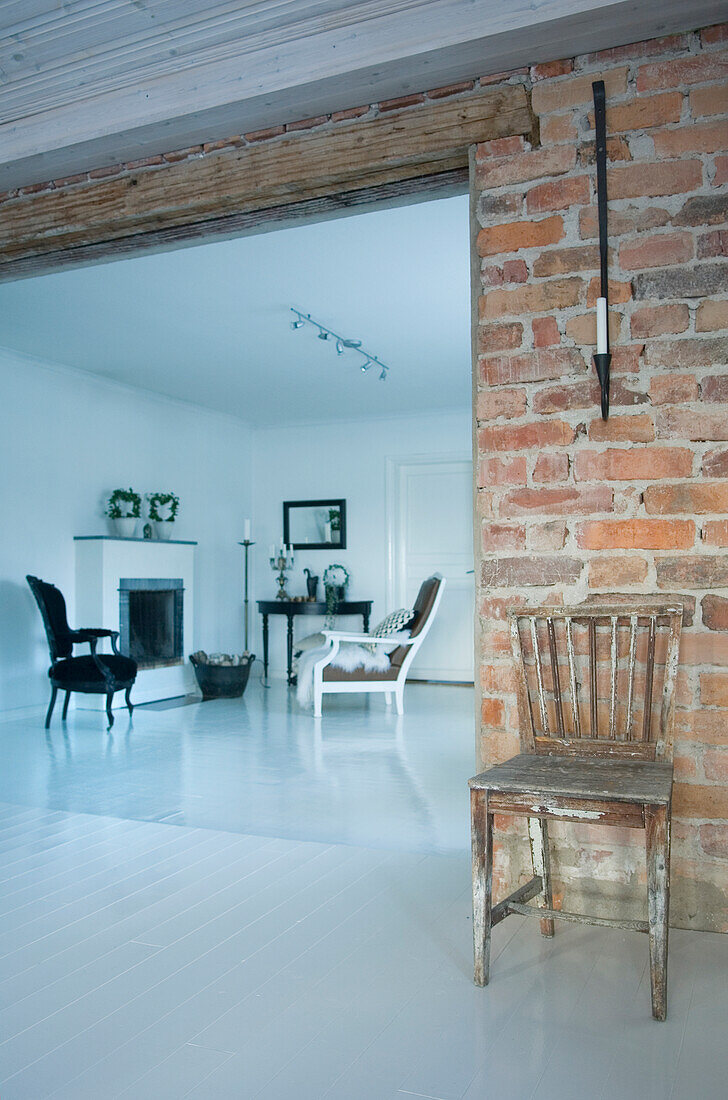 Living room with fireplace, brick wall and contrasting chairs