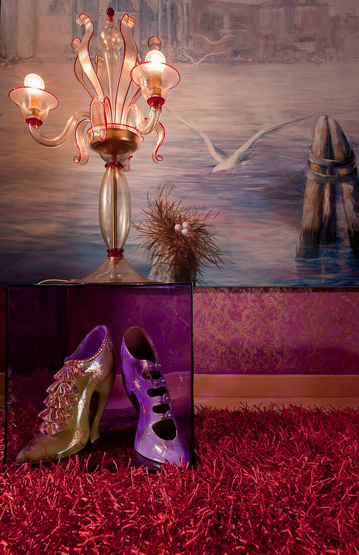 Venetian-style floor lamp and high heels in front of painted lagoon scenery