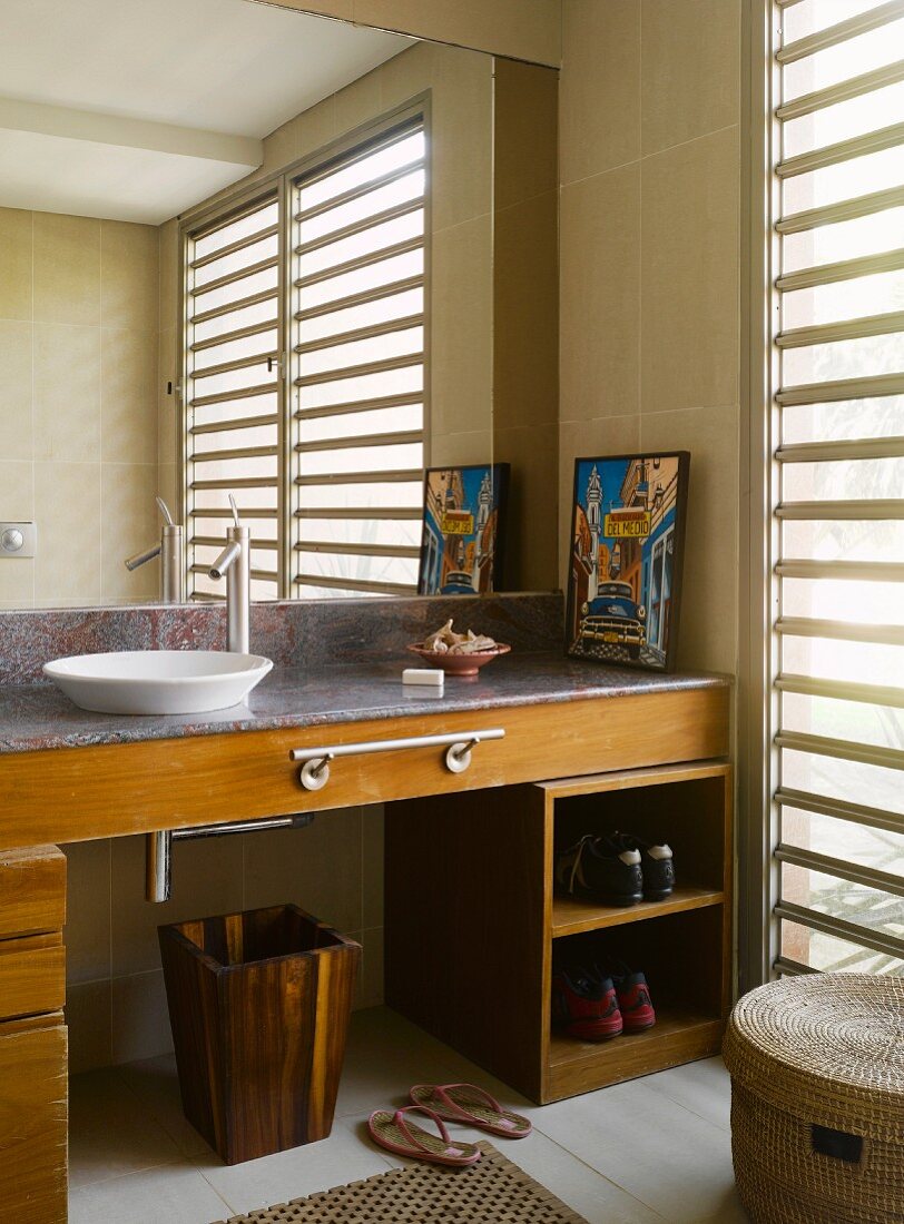 Grosser Badezimmerspiegel über Waschschüssel auf Waschtisch aus Holz und Stein mit Handtuchstange und Schuhregal