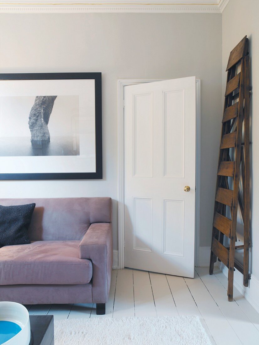 Living room with sofa beneath picture and ladder next to door