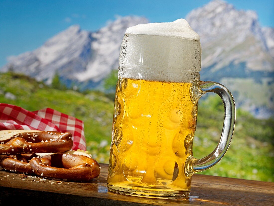 A beer and a pretzel in front of a mountain landscape