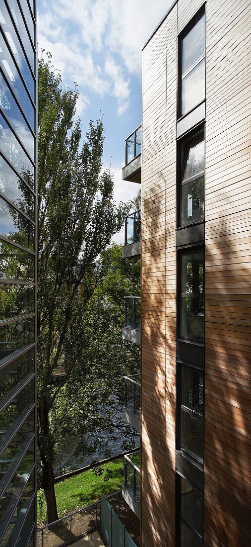 View of trees and river through narrow gap between tall, neighbouring buildings