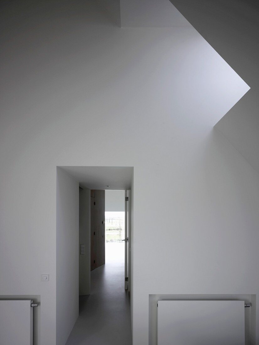 Foyer with skylight in sloping roof and view of corridor with light at the end