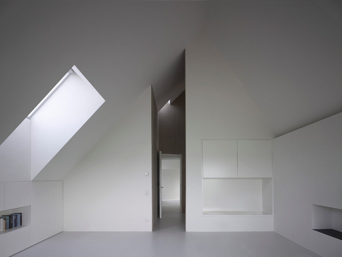 Integrierte Einbauschränke im modernen, weissen Dachraum und Blick in schmalen, hohen Flur mit offener Tür