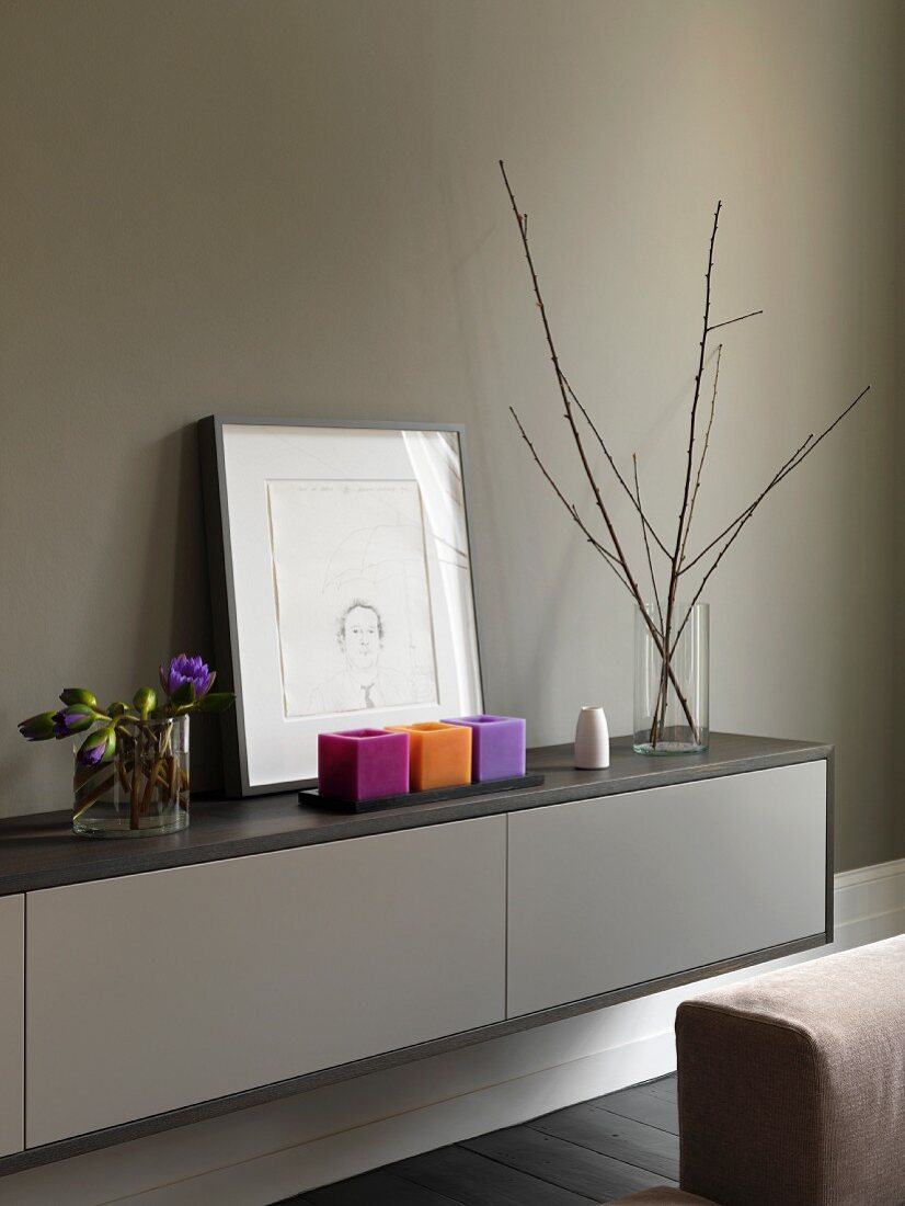 Sideboard with candles, a picture, flowers and twigs