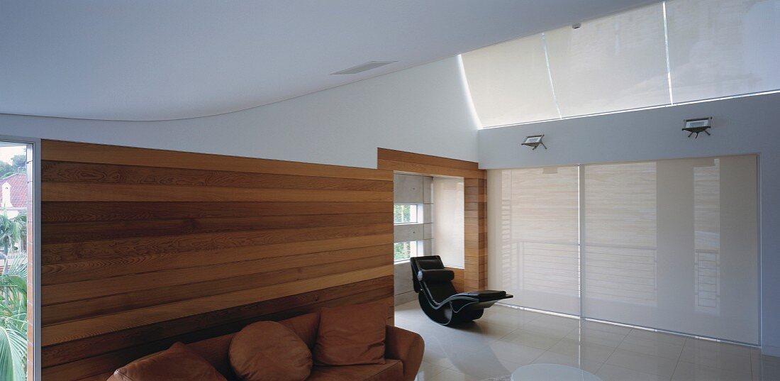 Living space with curved walls, wood panelling, sofa & chaise longue