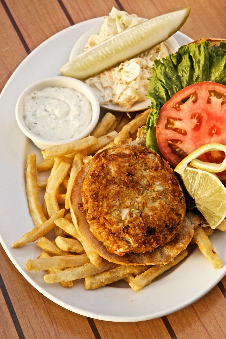 A crab cake with coleslaw, chips and a dip (USA)