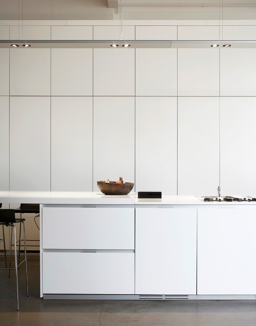 White kitchen with floor-to-ceiling fitted cupboards & recessed ceiling lamps