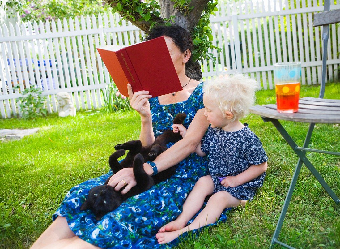 Mutter und Tochter sitzen im Gras im Garten