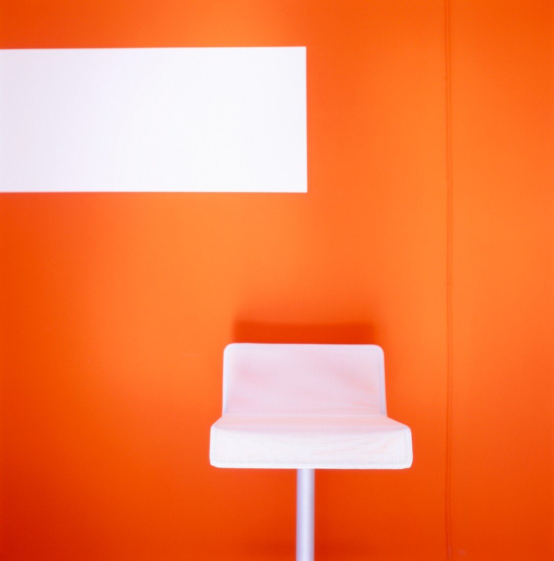 White barstool against orange wall