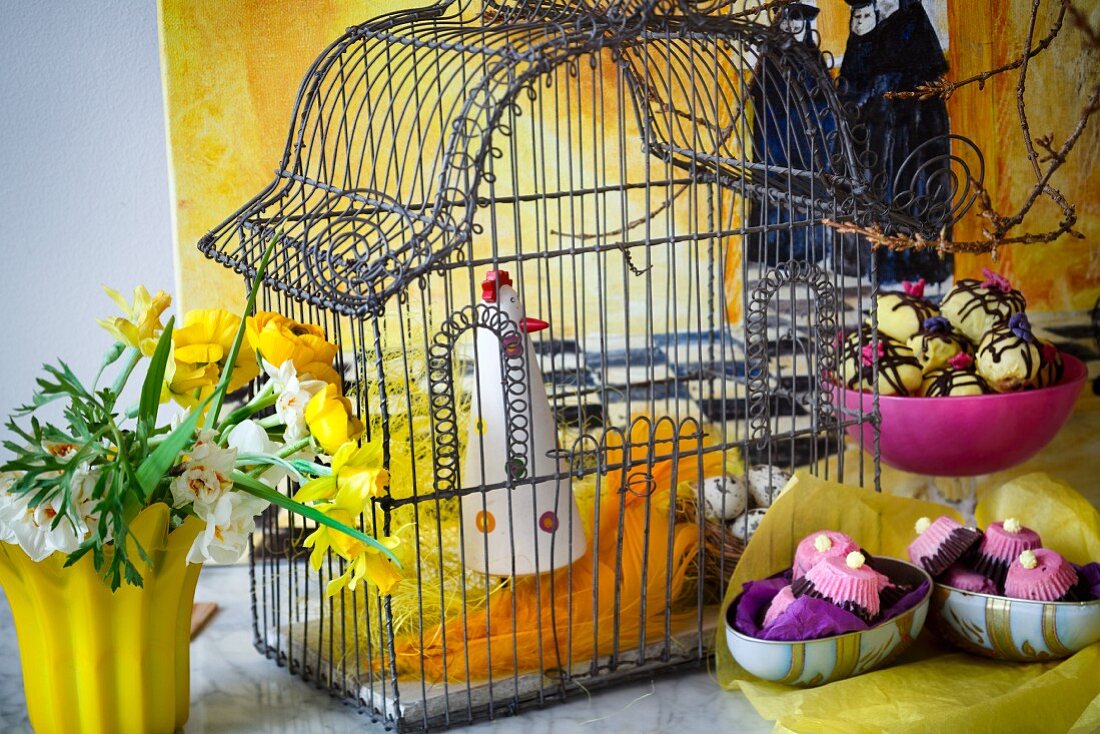 Easter decoration with bird cage, confectionary and flowers