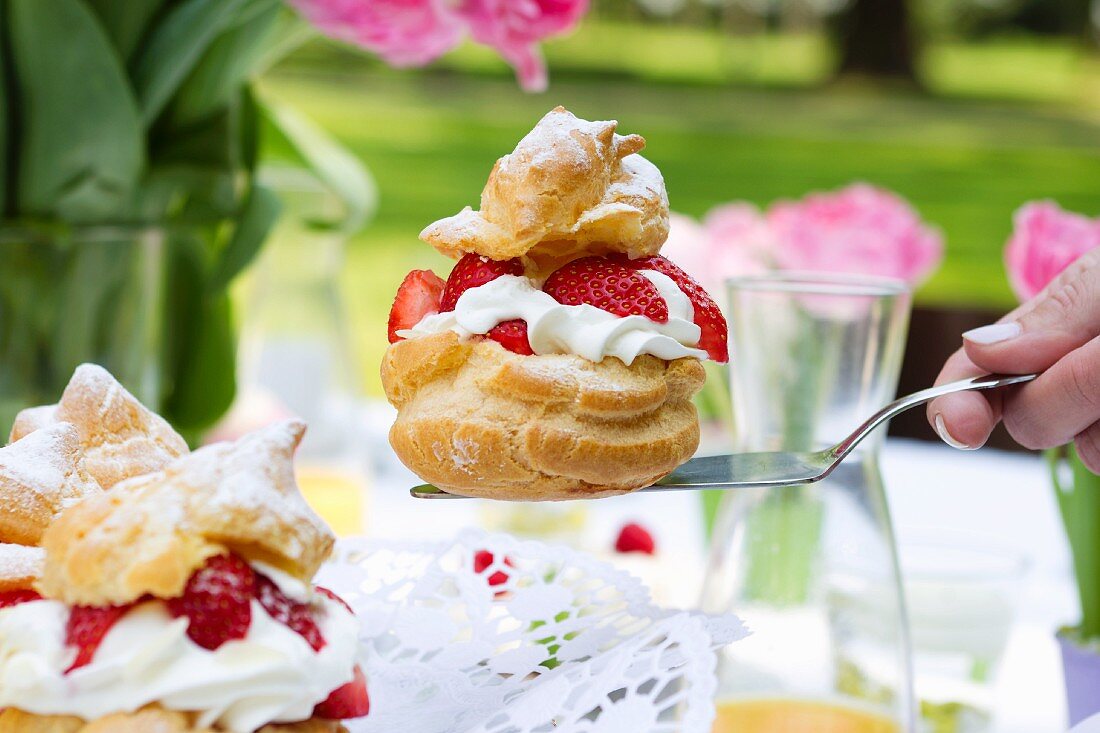 A profiterole filled with strawberries and cream on a cake slice