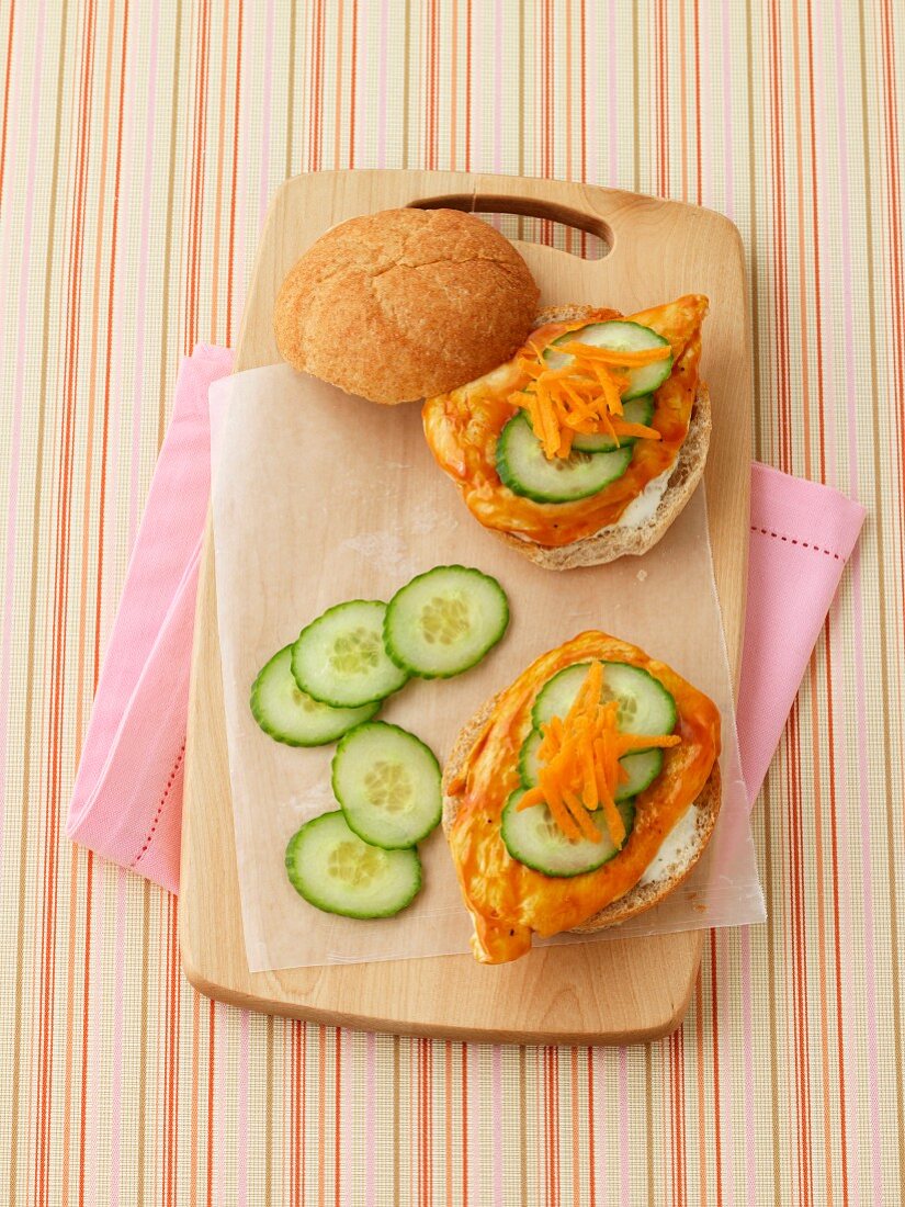 A chicken sandwich with cucumber and carrots