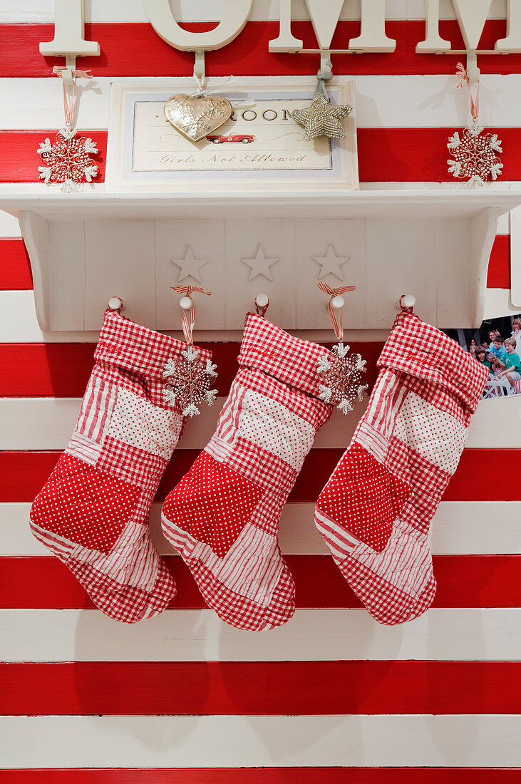 Christmas stockings hanging from bracket shelf on red and white striped wall