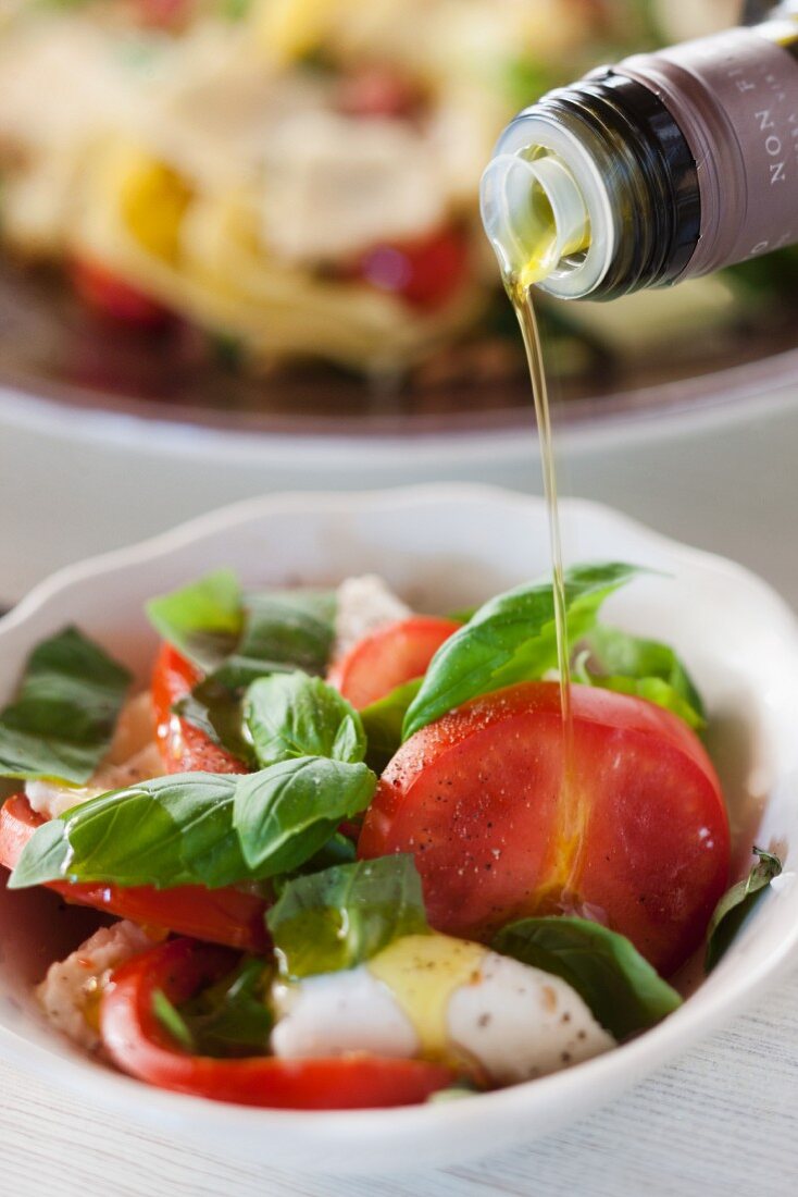 Sprinkling insalata caprese with olive oil
