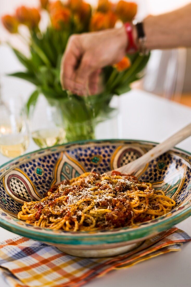 Spaghetti mit Tomatensauce und Pancetta wird mit Parmesan bestreut