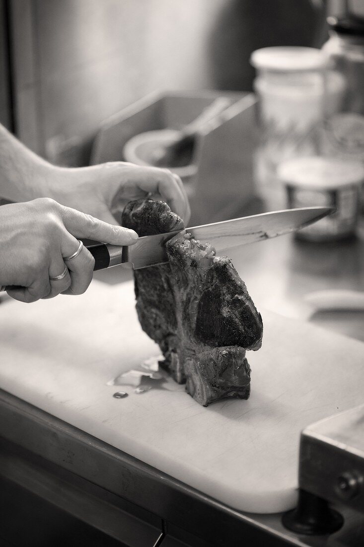 Gebratenes T-Bone-Steak demKnochen entlang in Stücke schneiden